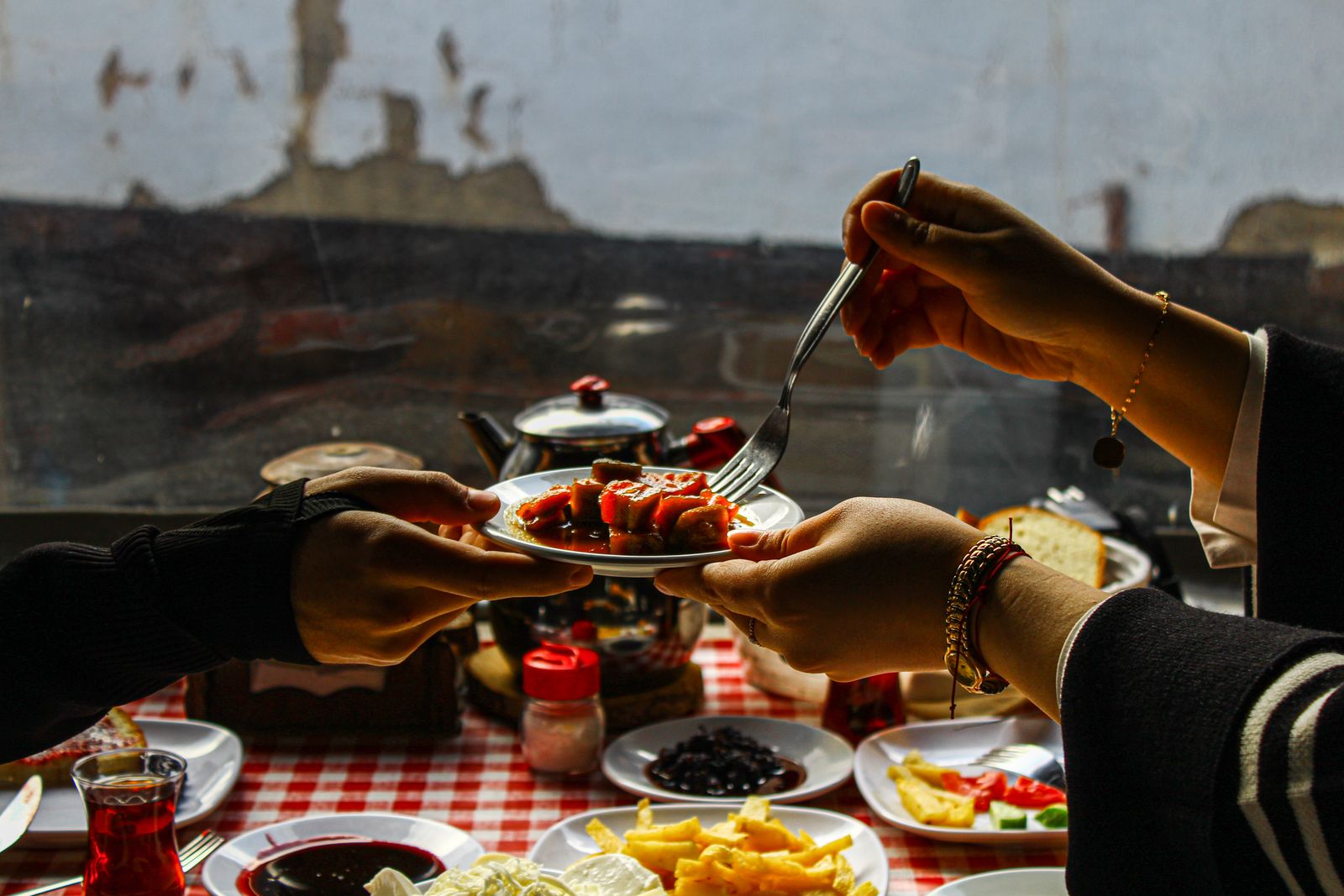 Hands sharing a plate around a breakfast table